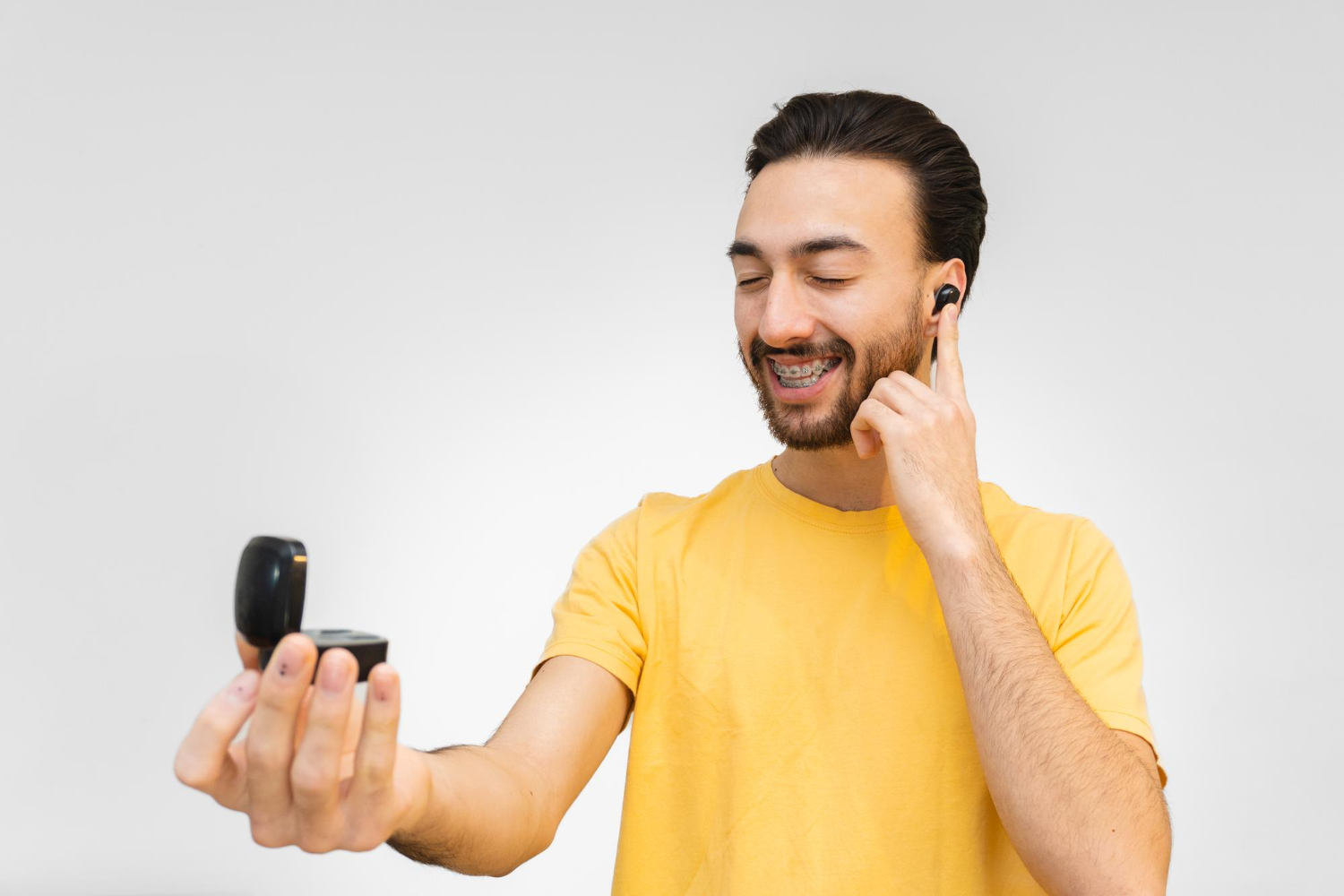 young-latin-man-smiling-with-wireless-touchsensitive-ear-buds-out-rechargeable-case-white-background